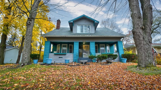 bungalow-style house featuring covered porch and a chimney