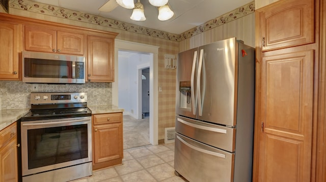 kitchen featuring backsplash, wallpapered walls, stainless steel appliances, and light countertops