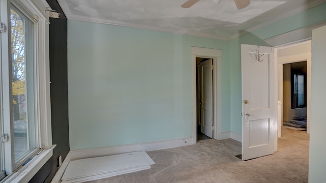 unfurnished room featuring crown molding, light colored carpet, and ceiling fan