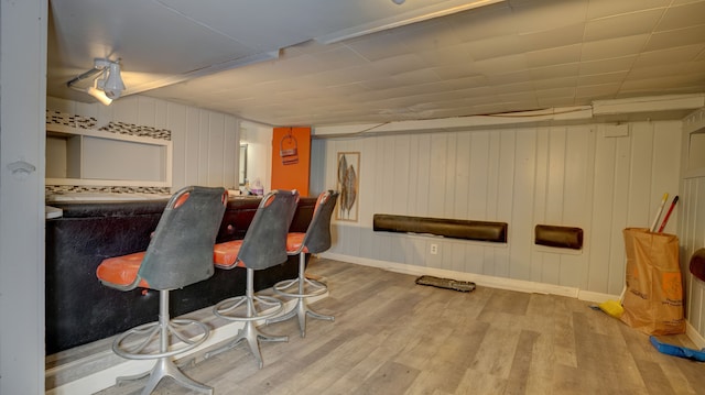 bar featuring a bar, wood finished floors, and baseboards