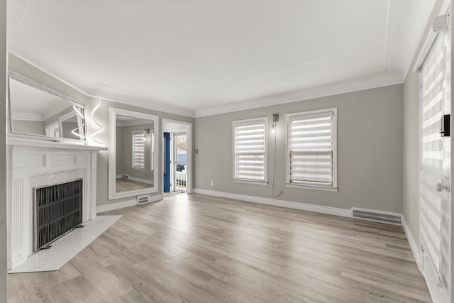 unfurnished living room with ornamental molding and light wood-type flooring