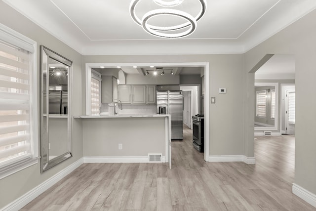 kitchen with kitchen peninsula, a wealth of natural light, stainless steel appliances, and light hardwood / wood-style floors