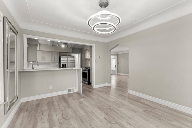 unfurnished living room with an inviting chandelier and light hardwood / wood-style flooring