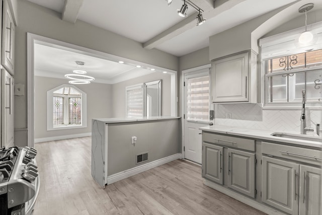 kitchen featuring pendant lighting, sink, light hardwood / wood-style floors, stainless steel range, and beam ceiling