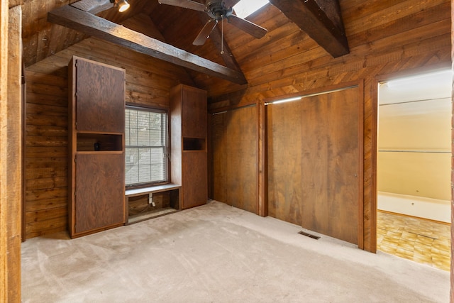 interior space with wood walls, vaulted ceiling with beams, ceiling fan, light colored carpet, and wood ceiling