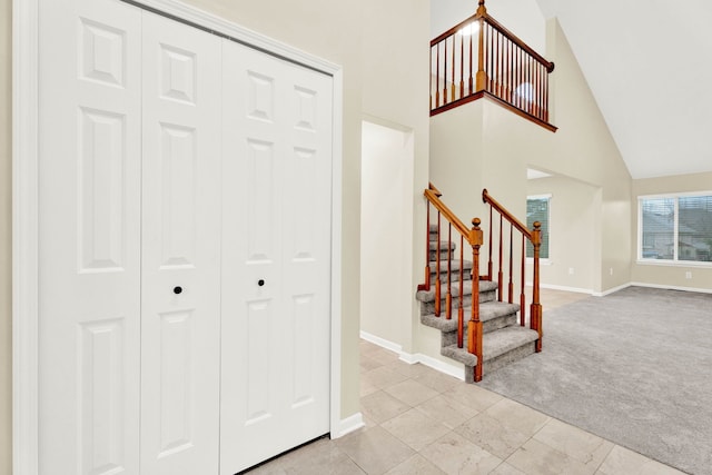 carpeted entrance foyer featuring high vaulted ceiling