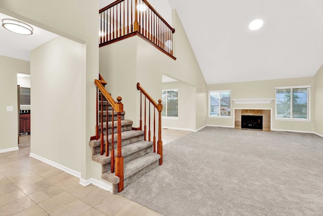 carpeted living room with a tiled fireplace and high vaulted ceiling