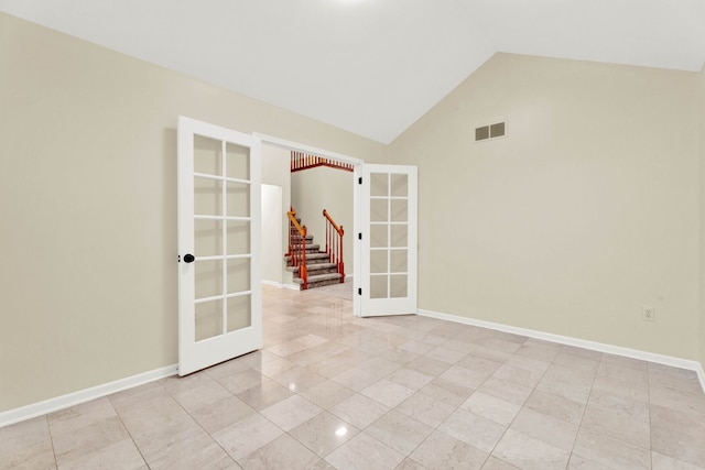 empty room with french doors, light tile patterned flooring, and vaulted ceiling