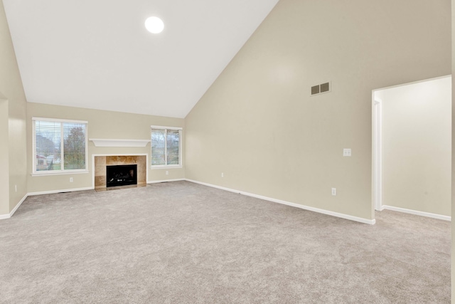 unfurnished living room with carpet flooring, a tile fireplace, and high vaulted ceiling