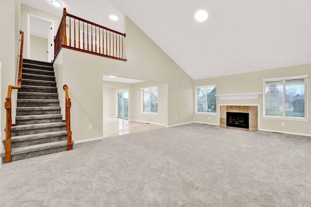 unfurnished living room featuring a fireplace, high vaulted ceiling, and light colored carpet