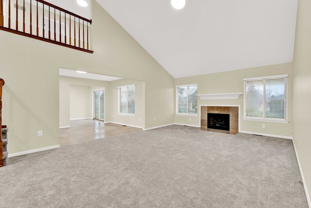 unfurnished living room with a tiled fireplace, light carpet, and high vaulted ceiling