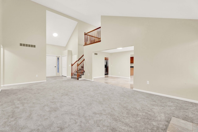 unfurnished living room with light carpet and high vaulted ceiling