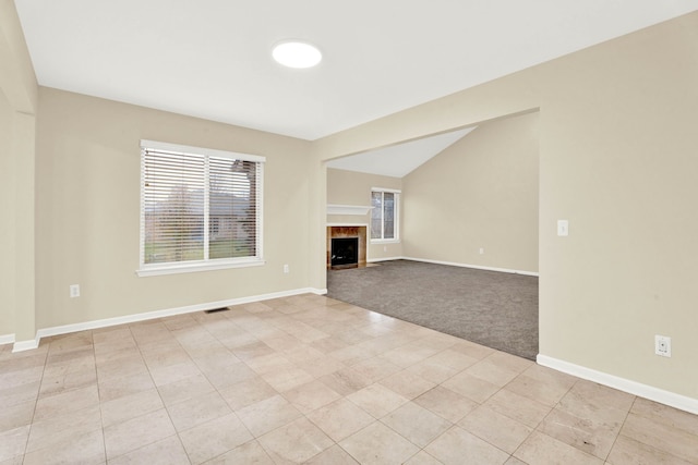 unfurnished living room featuring light colored carpet, lofted ceiling, and a tiled fireplace