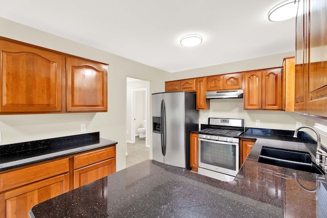 kitchen with dark stone countertops, sink, and stainless steel appliances