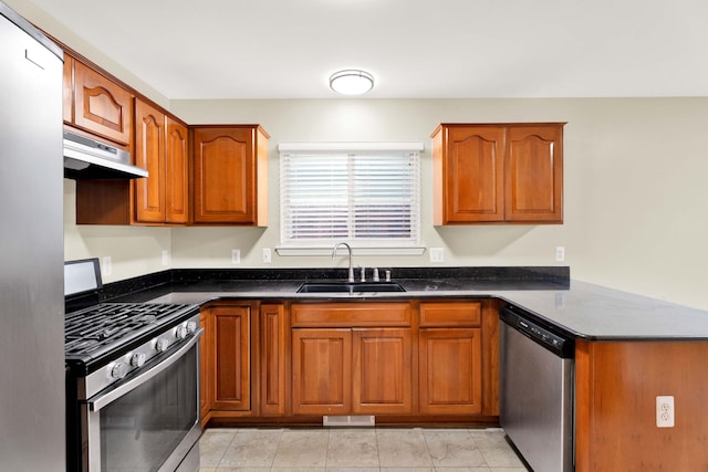 kitchen with light tile patterned flooring, appliances with stainless steel finishes, dark stone counters, and sink