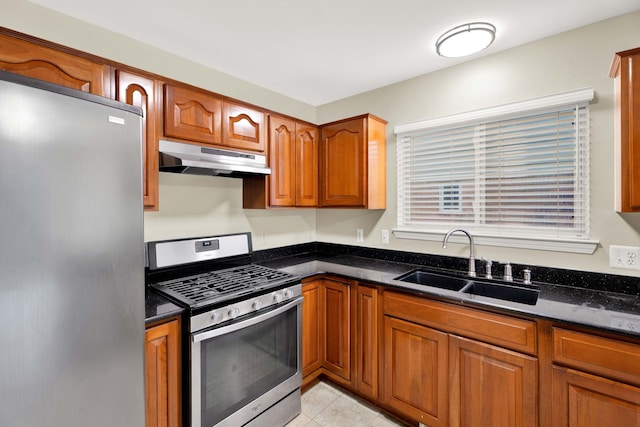 kitchen with dark stone countertops, light tile patterned floors, sink, and appliances with stainless steel finishes