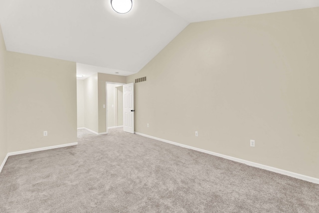 carpeted spare room with vaulted ceiling