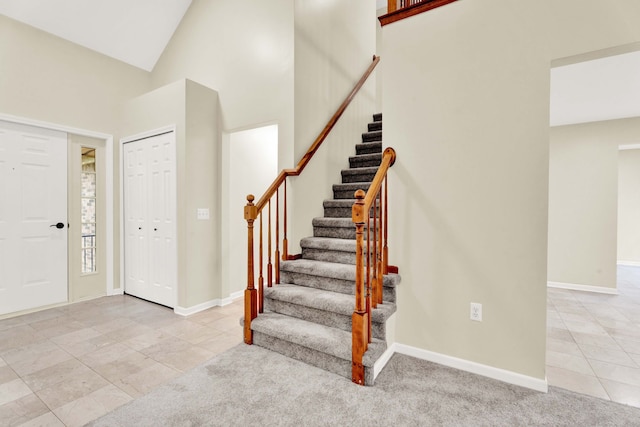 carpeted entrance foyer featuring high vaulted ceiling