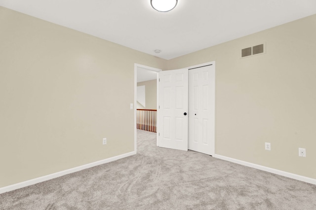 unfurnished bedroom with a closet and light colored carpet