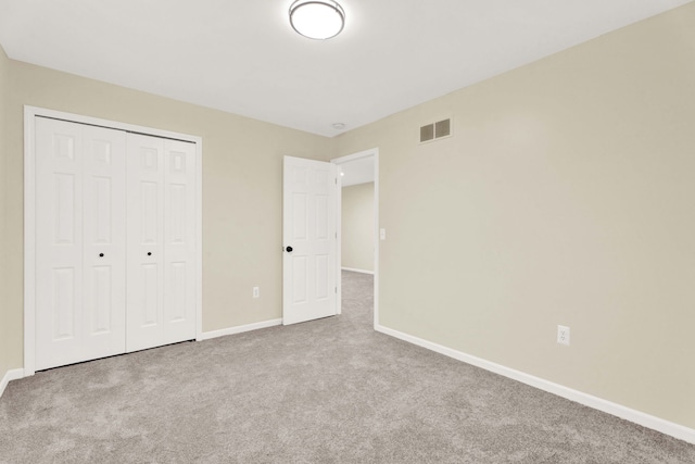 unfurnished bedroom with light carpet and a closet