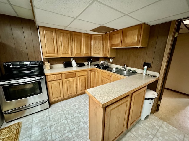 kitchen featuring a drop ceiling, kitchen peninsula, sink, and stainless steel range