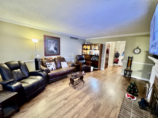 living room featuring a textured ceiling, light hardwood / wood-style floors, crown molding, and a brick fireplace