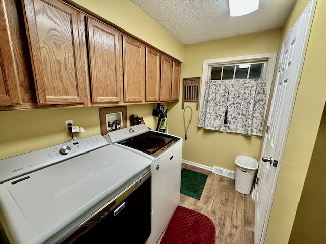 laundry room with cabinets, light hardwood / wood-style flooring, washer and dryer, and a textured ceiling