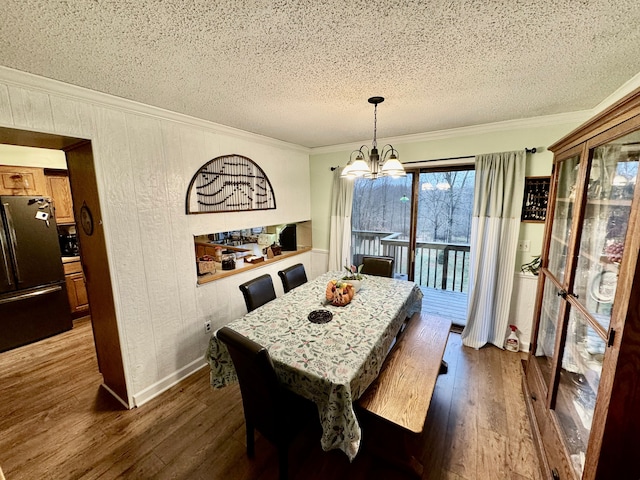 dining room featuring hardwood / wood-style floors, a textured ceiling, crown molding, and a notable chandelier