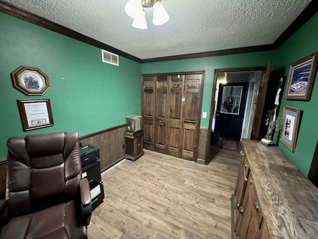 office with light hardwood / wood-style floors, a textured ceiling, and ornamental molding