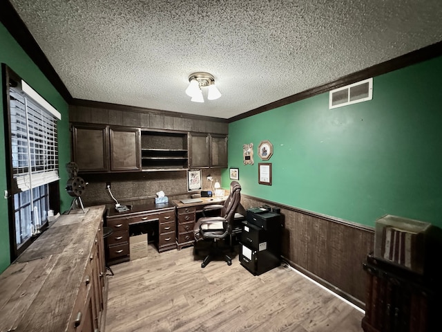 office with a textured ceiling, light hardwood / wood-style floors, crown molding, and wood walls