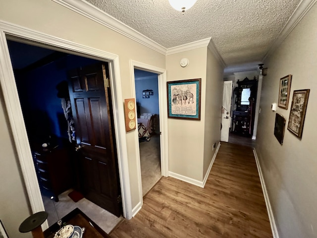 hallway with hardwood / wood-style floors, a textured ceiling, and ornamental molding