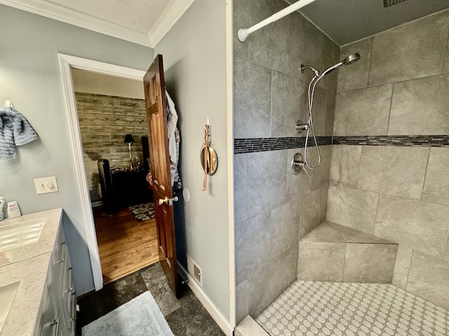 bathroom with vanity, wood-type flooring, ornamental molding, and tiled shower