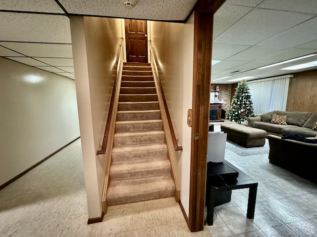 stairway featuring a paneled ceiling and a fireplace