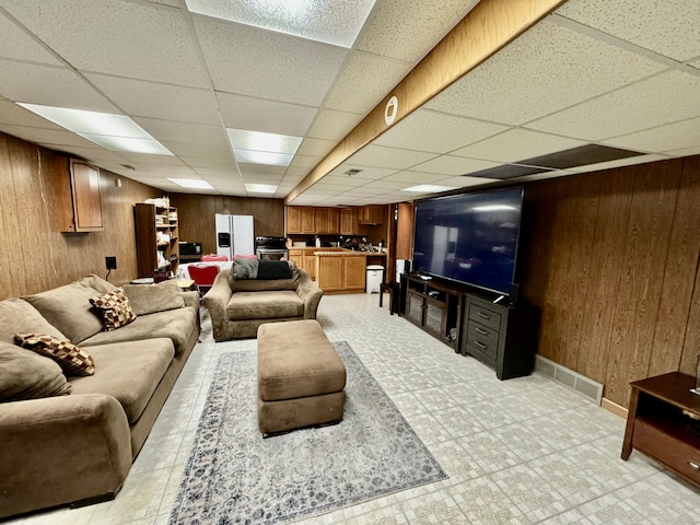 living room featuring a drop ceiling and wood walls