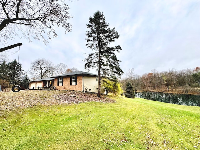 view of yard featuring an attached garage and a water view