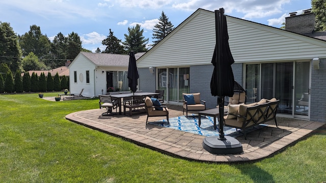 rear view of house with a yard, an outdoor living space, and a patio