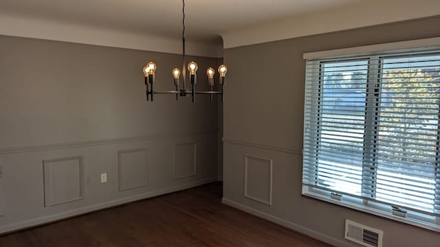 unfurnished dining area featuring an inviting chandelier and dark wood-type flooring