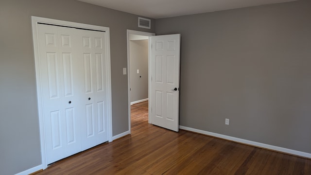 unfurnished bedroom featuring dark wood-type flooring and a closet