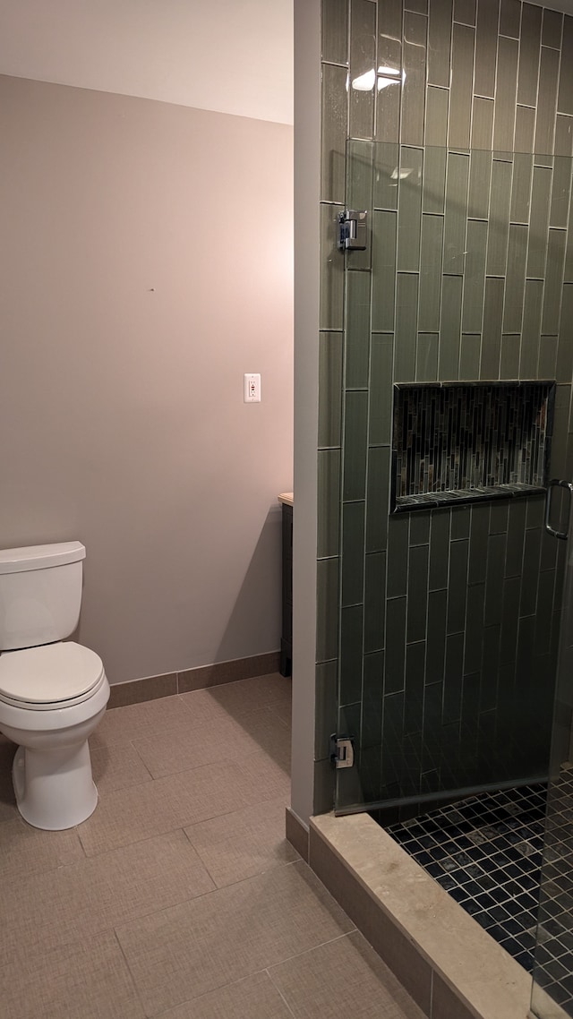 bathroom featuring a tile shower, toilet, and tile patterned floors