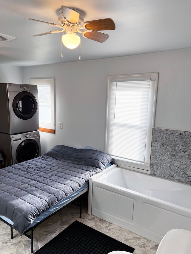 bedroom with stacked washer / dryer and ceiling fan