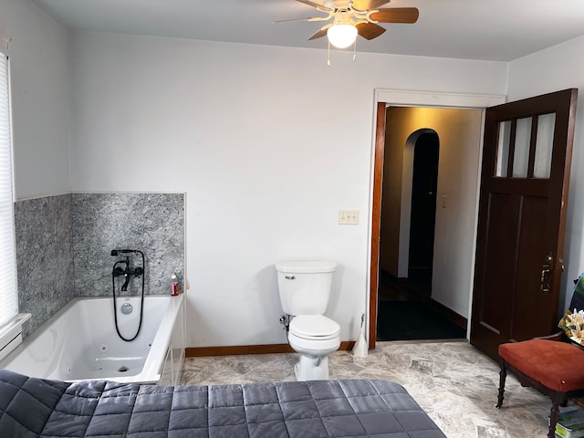 bathroom featuring a tub, ceiling fan, and toilet