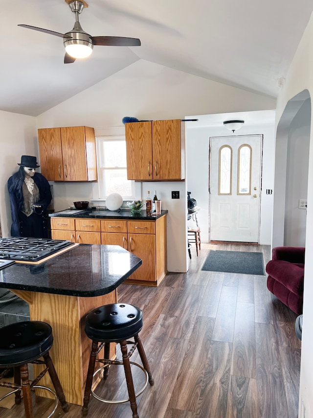 kitchen with a breakfast bar area, dark hardwood / wood-style flooring, lofted ceiling, and gas stovetop