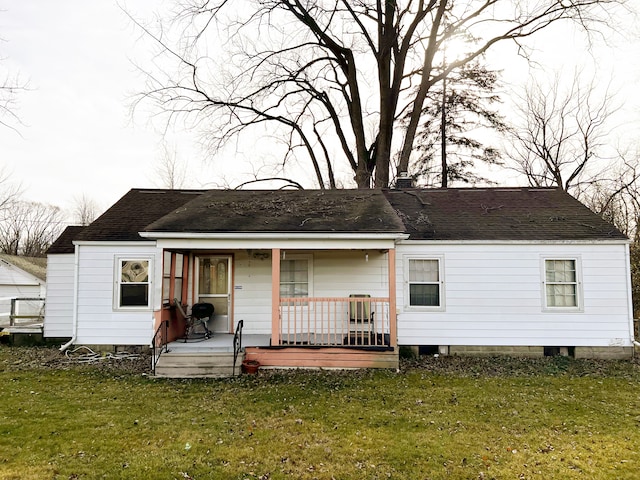 back of house with covered porch and a yard