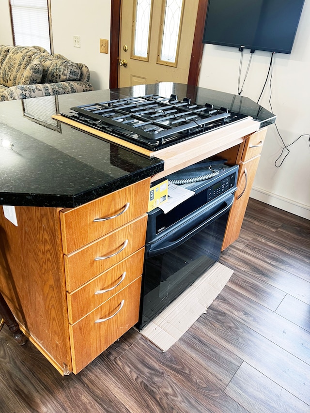 kitchen featuring dark hardwood / wood-style floors, oven, and black gas stovetop