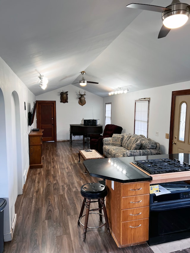 kitchen featuring ceiling fan, gas stovetop, wall oven, dark hardwood / wood-style flooring, and vaulted ceiling