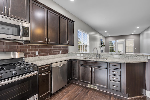 kitchen with sink, stainless steel appliances, dark hardwood / wood-style flooring, kitchen peninsula, and dark brown cabinets