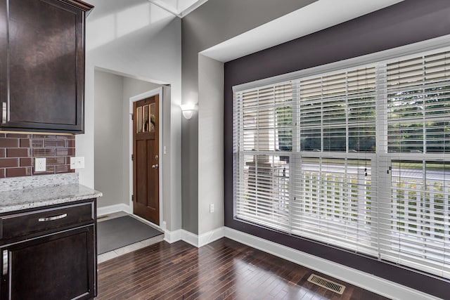 interior space featuring light stone countertops, dark hardwood / wood-style flooring, backsplash, and dark brown cabinetry