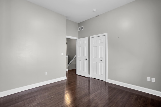 unfurnished bedroom featuring dark hardwood / wood-style floors and a towering ceiling