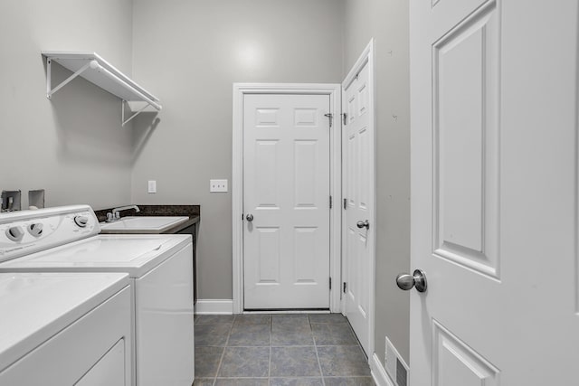 washroom featuring separate washer and dryer, dark tile patterned flooring, and sink