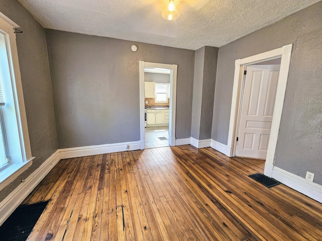 unfurnished room featuring hardwood / wood-style flooring and a textured ceiling